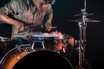 musician playing drums with splashes, black background with beautiful soft light