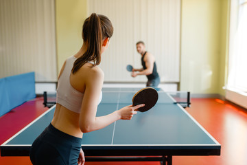 Man and woman playing ping pong indoors