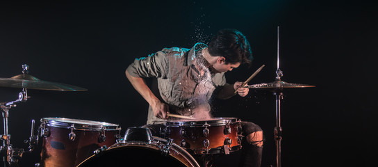 musician playing drums with splashes, black background with beautiful soft light