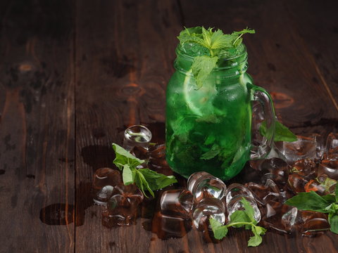 Cocktail with mint, lime and ice on a wooden table