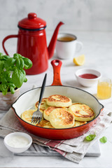 Curd pancakes in a red frying pan. Cottage cheese fritters or Syrniki for breakfast
