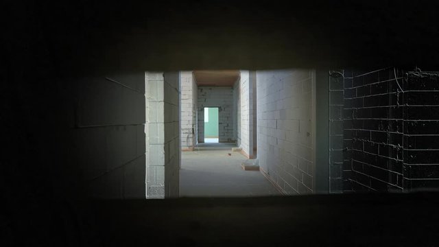 Search in the dark with a lantern. The hero of a computer game is looking for a target in an unfinished building. Abandoned building with many rooms. Simulation of computer video game shooter. Arcade