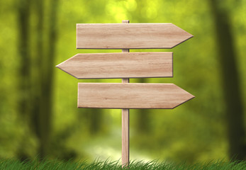 Wooden direction triple arrow roadsign with forest background