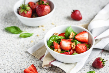 Fresh spinach salad with strawberries and nuts on a gray background. Summer salad with strawberries