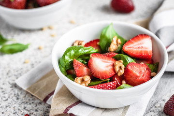Fresh spinach salad with strawberries and nuts on a gray background. Summer salad with strawberries