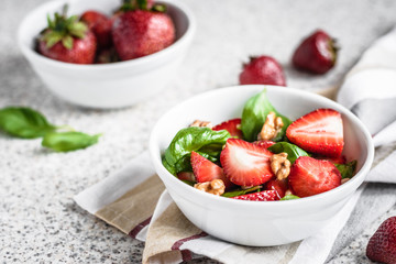 Fresh spinach salad with strawberries and nuts on a gray background. Summer salad with strawberries
