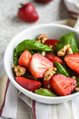 Fresh spinach salad with strawberries and nuts on a gray background. Summer salad with strawberries