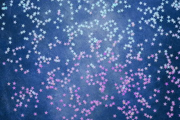 Holographic stars confetti on blue background. Festive backdrop for your projects