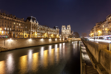 Notre Dame Cathedral and the Seine river in Paris at night, France.