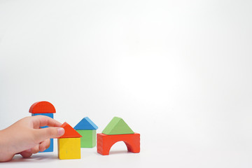 Hand holding a colored wooden toy block on white background.