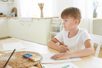 Creativity, leisure, hobby, art and imagination concept. Picture of thoughtful Caucasian schoolboy...