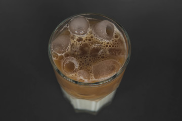 large transparent glass filled with cold summer drink coffee with milk photographed on the isolated gray background picture for the menu.