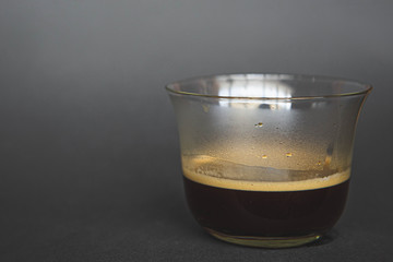 large transparent glass filled with of aromatic filter Turkish coffee photographed on the isolated gray background picture for the menu.