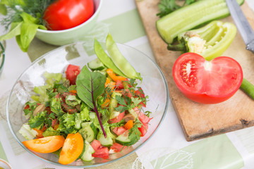 Plate with fresh mixed vegetables salad with greens close-up. Vegan vegetarian healthy food 