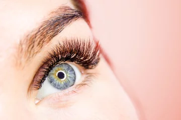 Beschnittenes Frauengesicht mit augenlangen falschen Wimpern, Nahaufnahme, getönt mit der trendigen Living Coral-Farbe des Jahres 2019. Platz für Text. - Schönheitssalon und Wimpernverlängerungsverfahren © FOTO_STOCKER