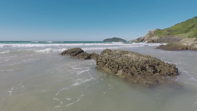 Movimento das ondas batendo contra a rocha na praia.