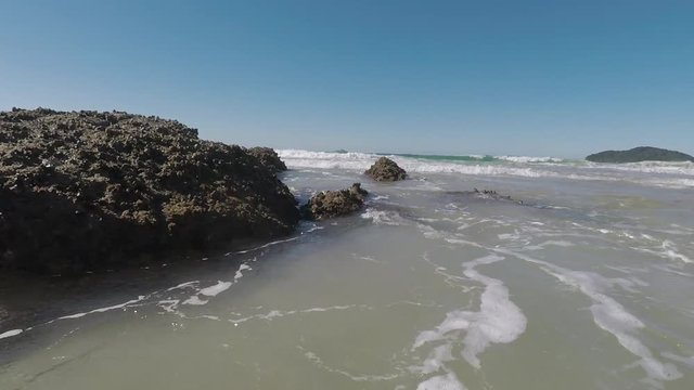 Movimento das ondas batendo contra a rocha na praia.