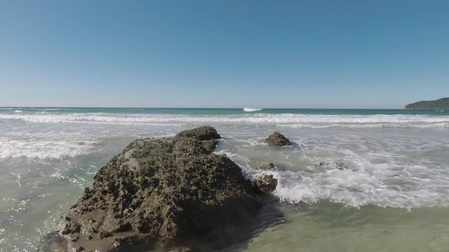 Movimento das ondas batendo contra a rocha na praia.