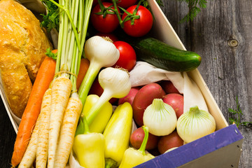 vegetables and a loaf of bread at wooden crate, top view