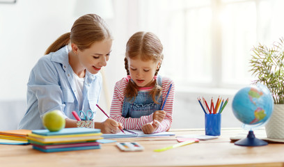 mother and child daughter doing homework writing and reading at home.