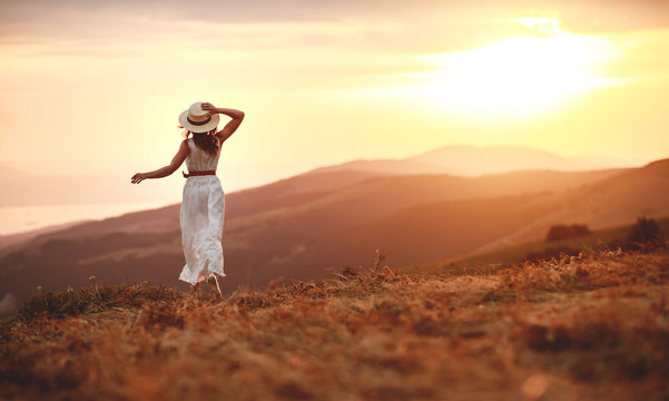 Happy woman standing with her back on sunset in nature iwith open hands