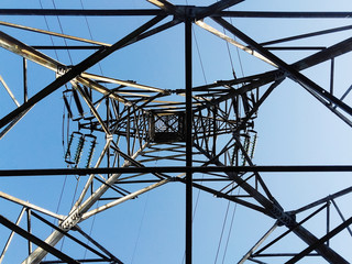 Low angle view of a high electricity pillar   from inside against blue sky