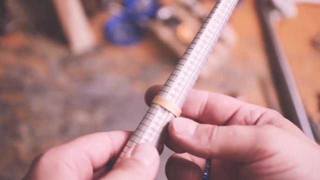 Close up of jeweler using ring mandrel to measure the size of wedding ring