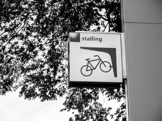 Stalling covered bicycle sign near the entrance of the public parking in central Harlem, Netherlands - black and white