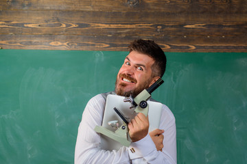 Happy student with laptop and microscope. Bearded man with notebook and microscope. Biology or chemistry lesson. Education, school, teaching. Research. Excited scientist with microscope and computer.