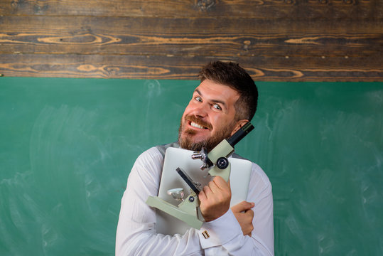 Happy student with laptop and microscope. Bearded man with notebook and microscope. Biology or chemistry lesson. Education, school, teaching. Research. Excited scientist with microscope and computer.