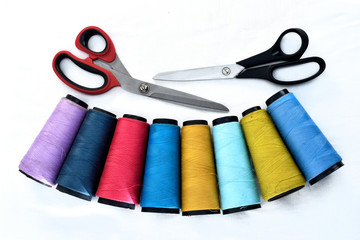 Colorful sewing thread reels on white background with scissors