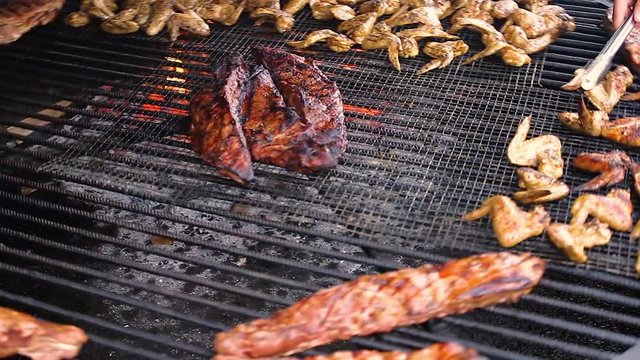 Big hot rolling barbecue grill, open fire stove. Chicken wings, pork steaks and ribs and other meat are well done roasted and cooked