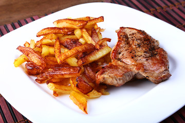 Grilled free-range beef steak with potato free, fresh tomatoes and sauce on a brown stone background
