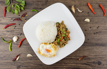 Spicy Thai basil with Crispy Chicken and Egg (Pad Krapow Gai) on table . it is a very delicious Thai food. Rice topped with stir-fried pork and basil leaves . street food in Thailand.