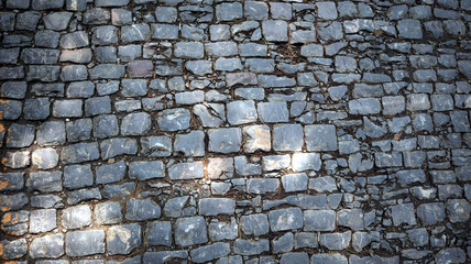 Top view on stone road close up. Old pavement of granite. Brown square cobblestone sidewalk. Mock up or vintage grunge texture. Granite cobblestoned pavement background. block concrete Texture.