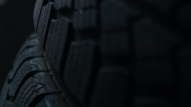close up studio shot of stacked new car tires. Blue light cinematic pedestal down shot with shallow depth of field