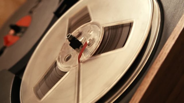 close up shot of spinning supply reel of old analog reel-to reel audio tape recorder, form of magnetic tape audio recorder in which the recording medium is held on a reel that is not in a cassette.