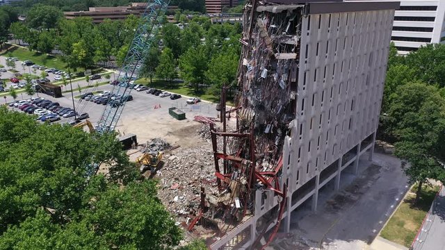 Aerial video of old office building being demolished by a wrecking ball taking apart the steel beams and concrete walls in Maryland United States