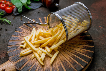 french fries on board on dark rustic concrete background