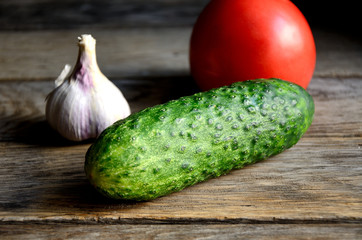 Garlic, tomato, cucumber on a wooden old table.