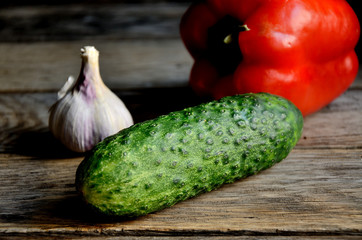 Garlic, sweet pepper, cucumber on a wooden old table.