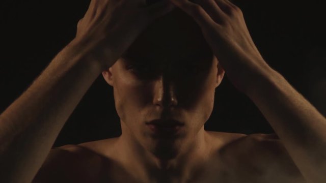 Sexy sport stripped guy in water drops with smoke on isolated black background