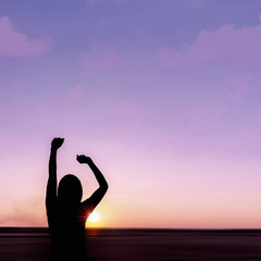 Silhouette of young woman at sunset on sea background.