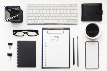 Notepad with 2020 goals, office stationery, and cup of coffee