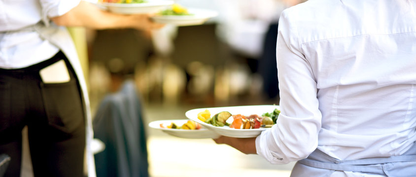 Bedienung serviert Essen für die Gäste im Restaurant