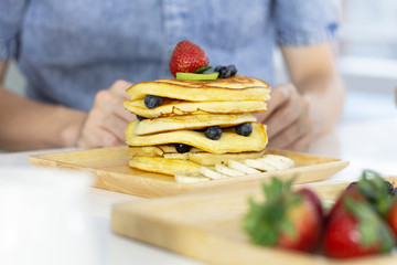 Morning breakfast in a cafe, pancakes with fresh fruits berries on white table.
