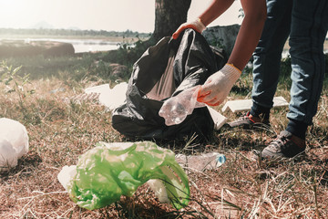 volunteer woman picking up garbage plastic for cleaning at river park