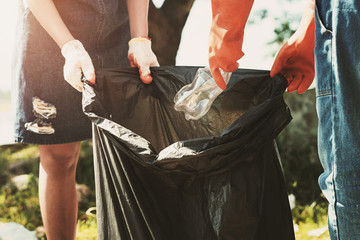 volunteer woman picking up garbage plastic for cleaning at river park