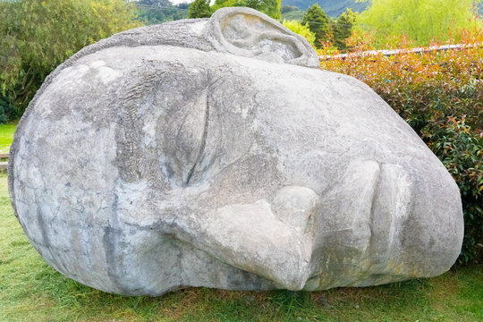 Colombia Tabio face carved in stone lying in the meadow close up