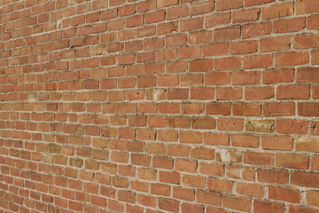 Antique weathered brick wall background in varying shades of reddish brown (angle view)